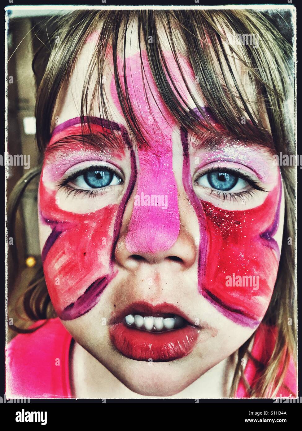 Girl with garish butterfly face paint. Stock Photo