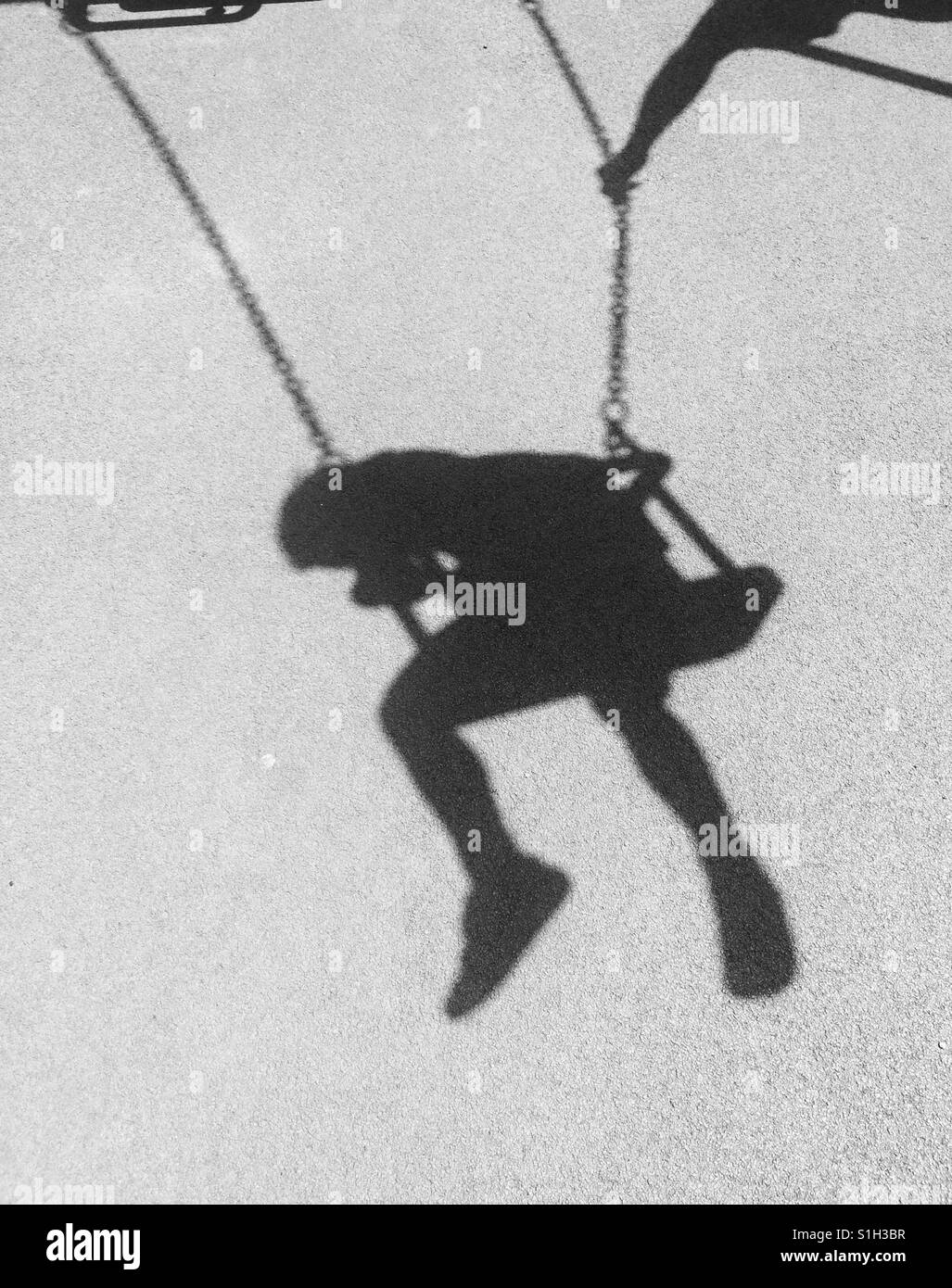 Shadow of a child on a swing and parents arm Stock Photo