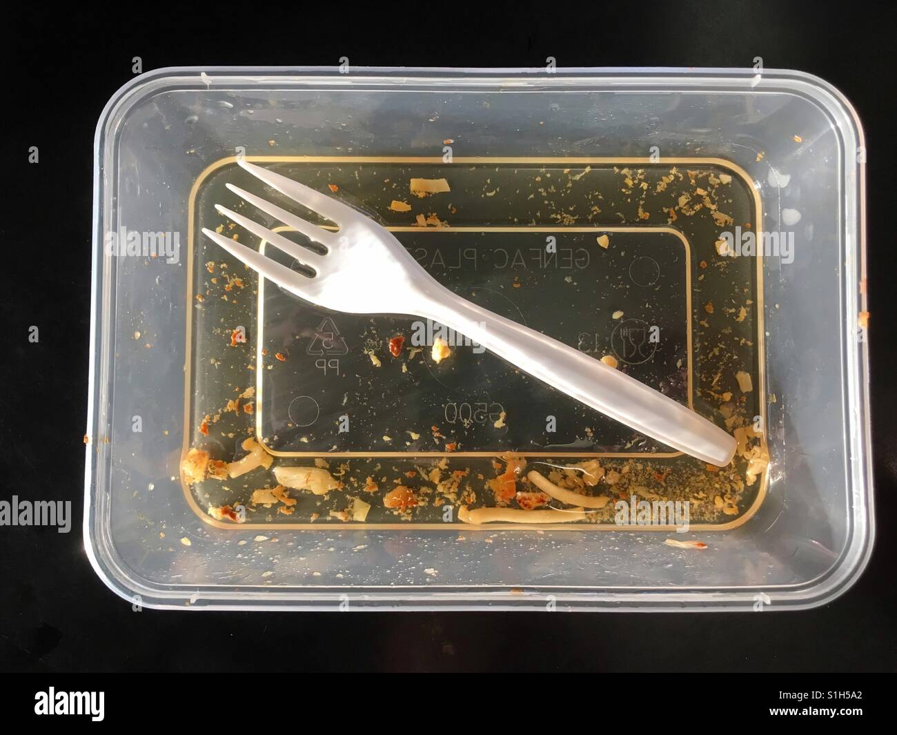 Fork inside an empty and greasy food takeaway plastic tube. - Smartphone Captured Stock Image