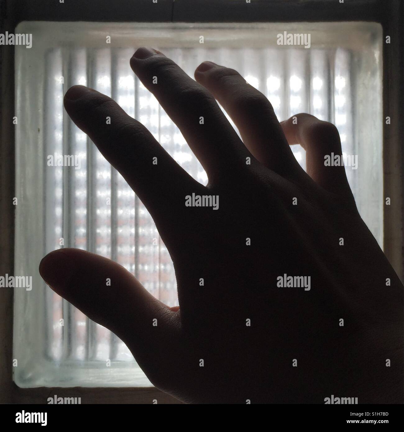 Hand reaching out to a frosted glass window. Stock Photo