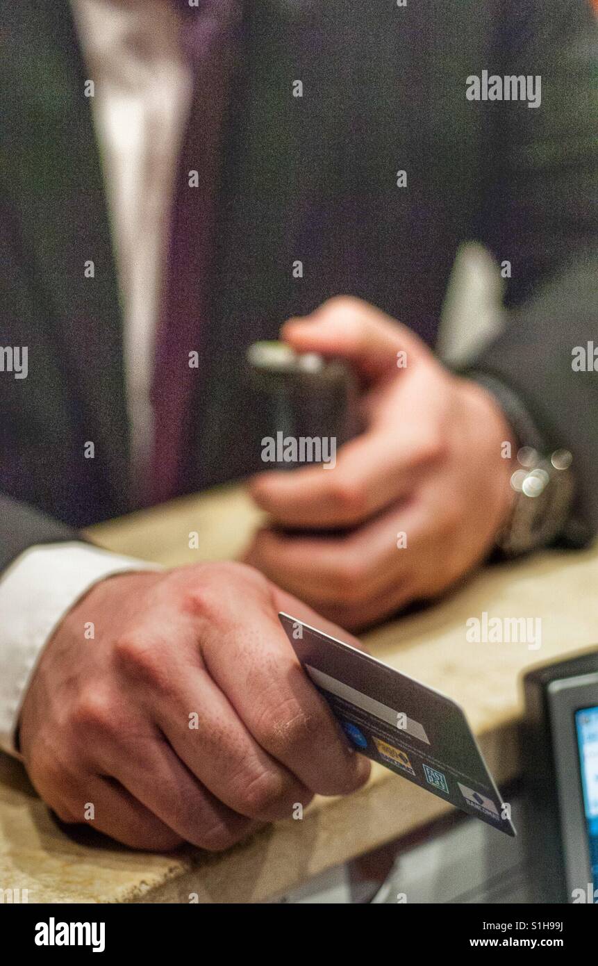 Detail of a man 's hand paying the bill with a credit card in a shop or restaurant - Smartphone Captured Stock Image
