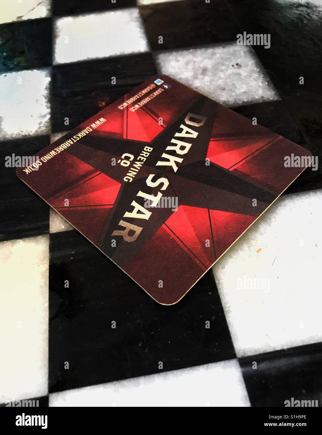 Dark Star beer mat on black and white chequered table Stock Photo