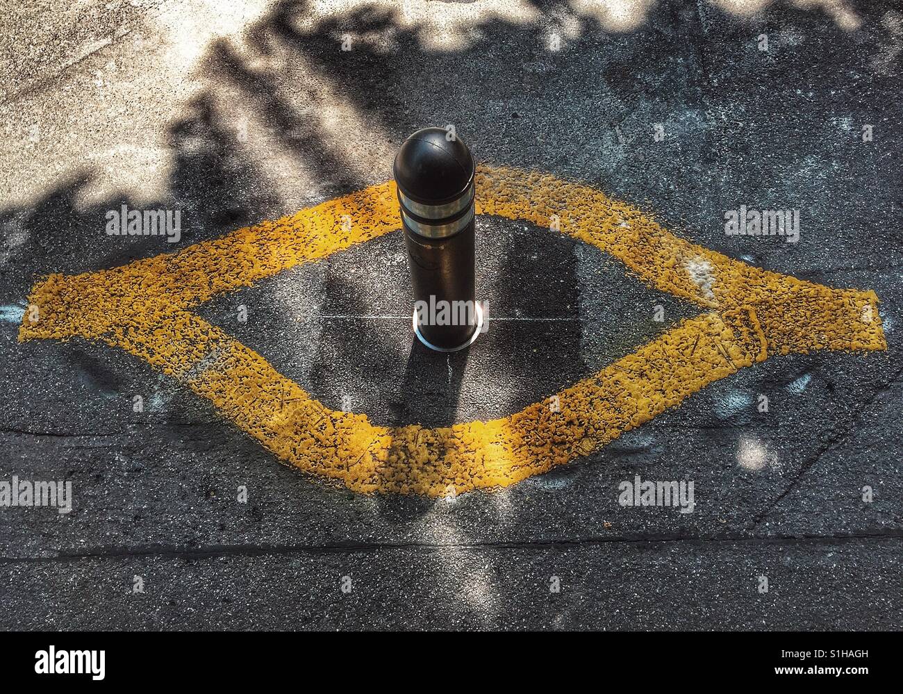 Bollard with yellow lines painted in shape of an eye - Smartphone Captured Stock Image
