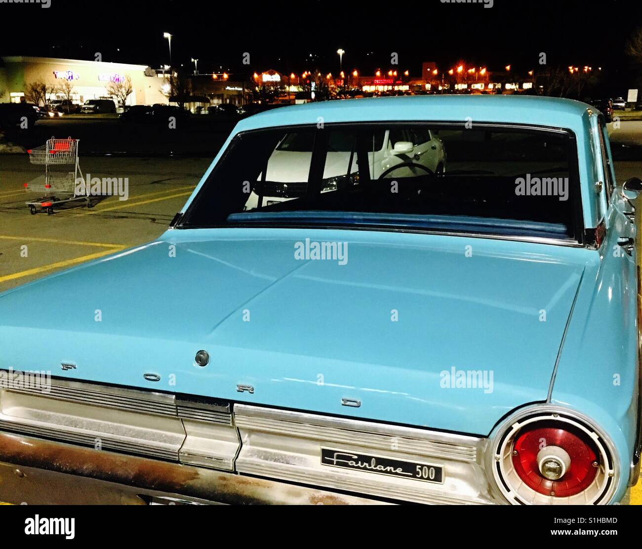 Aqua blue Ford Fairlane car 1960's in parking lot at night Stock Photo