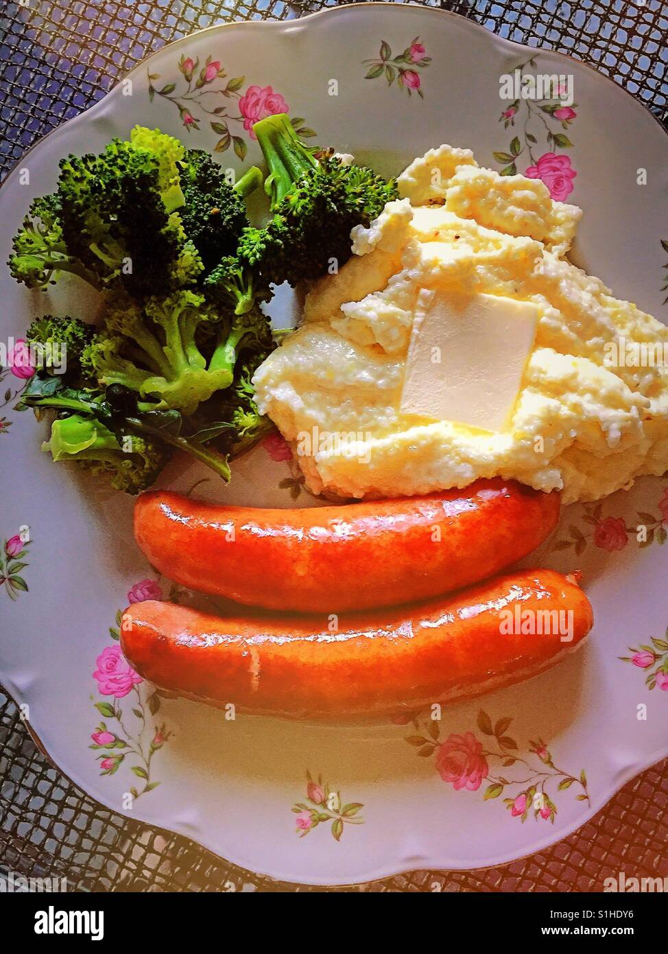 Hearty home cooked meal of sausages, grits and broccoli flowered  China plate, USA Stock Photo