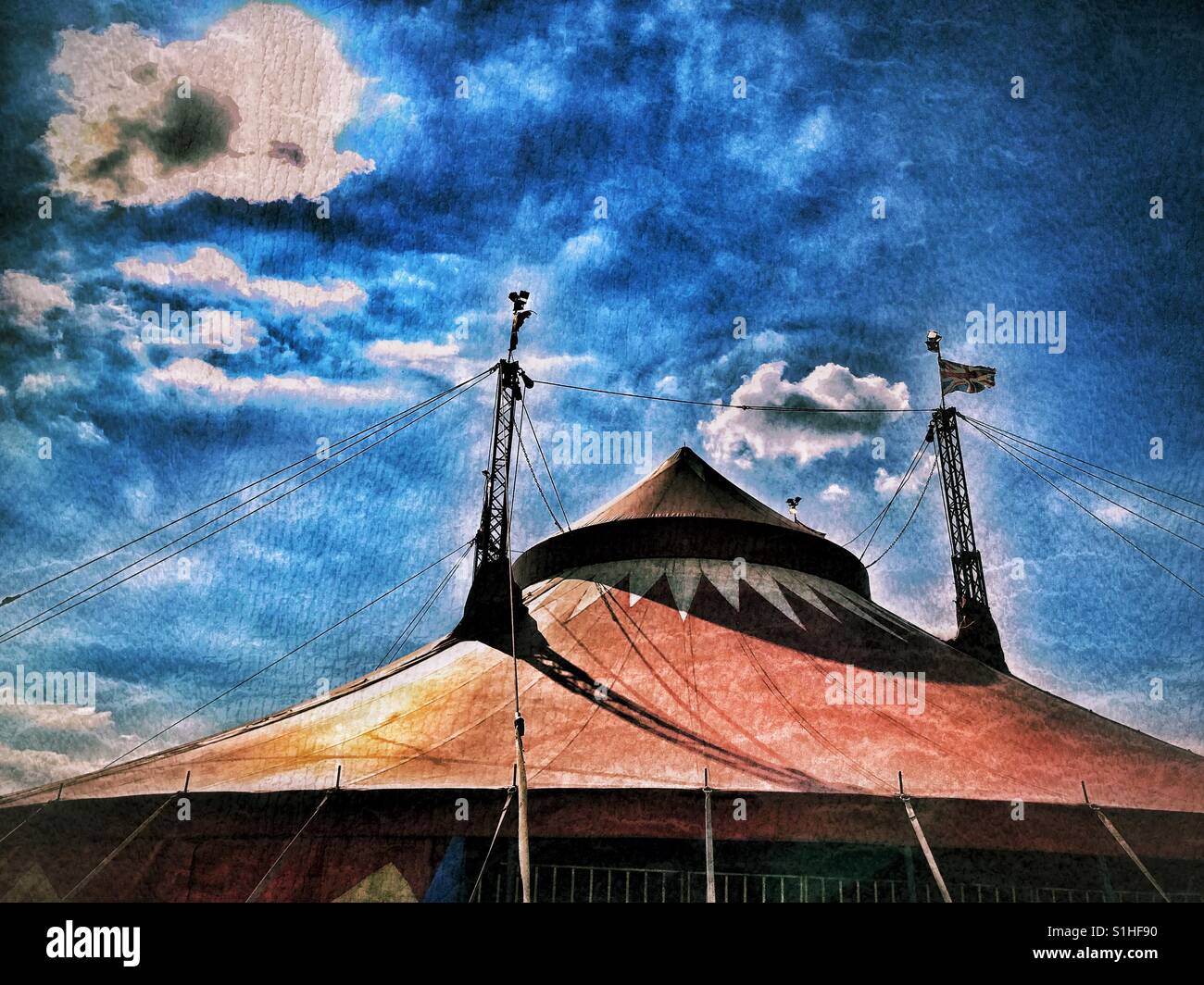 A grunge effect picture of the top of a circus tent. It's a hot summer's day in England, with blue sky and white clouds. Photo Credit - © COLIN HOSKINS. - Smartphone Captured Stock Image