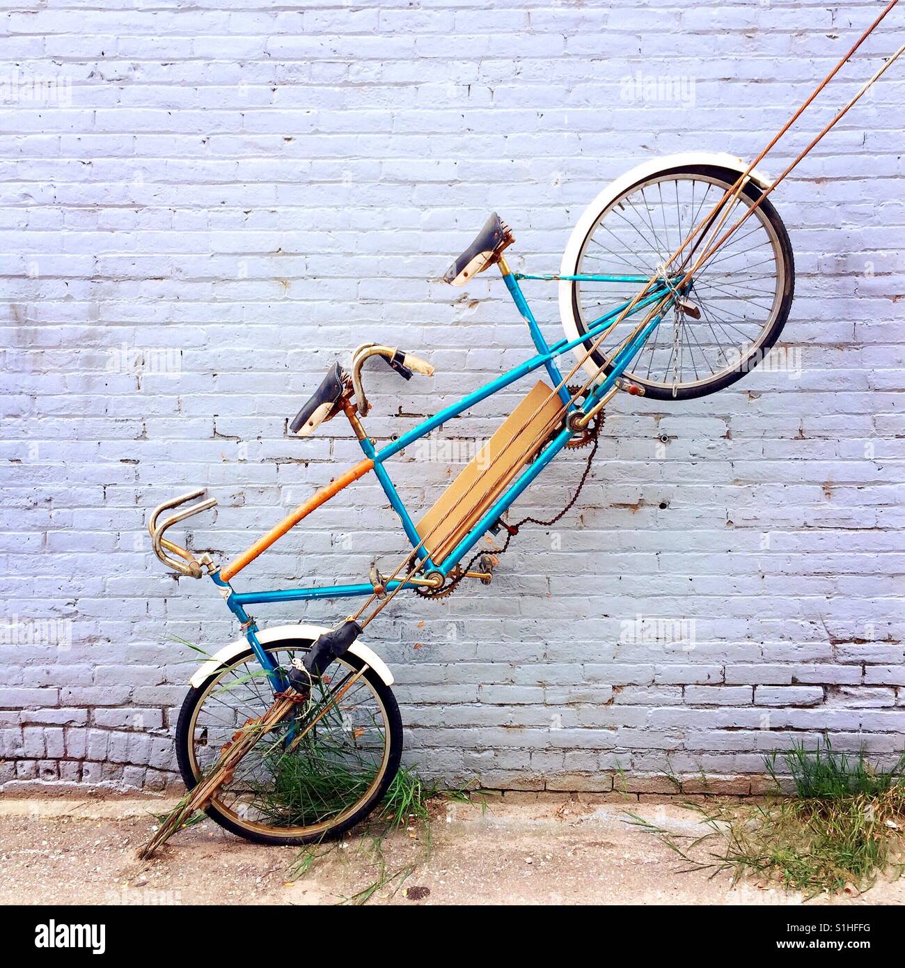 And old dilapidated tandem bicycle displayed on a brick wall Stock Photo