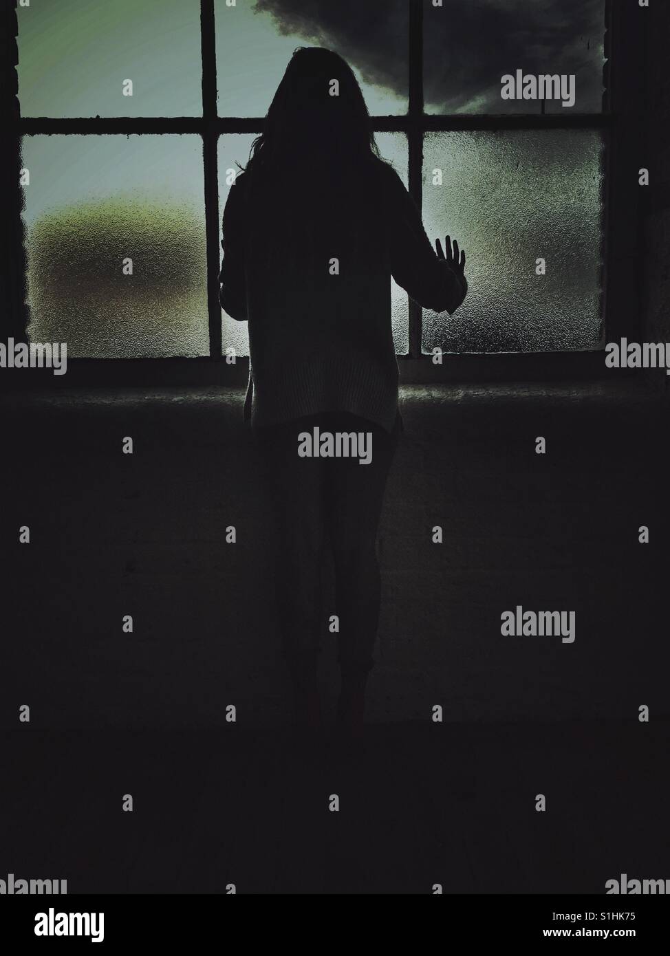 Rear view silhouette of a woman standing by the window - Smartphone Captured Stock Image