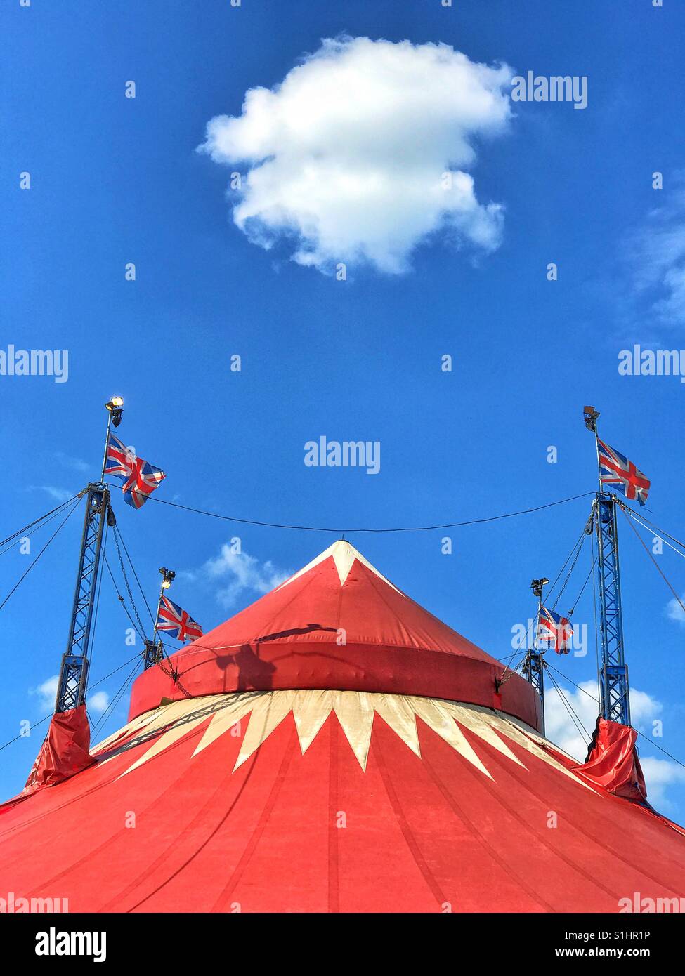 A lone fluffy white cloud hangs over the top of a circus tent during Summer in The United Kingdom. It's nearly time for Circus fun! Photo Credit - © COLIN HOSKINS. - Smartphone Captured Stock Image