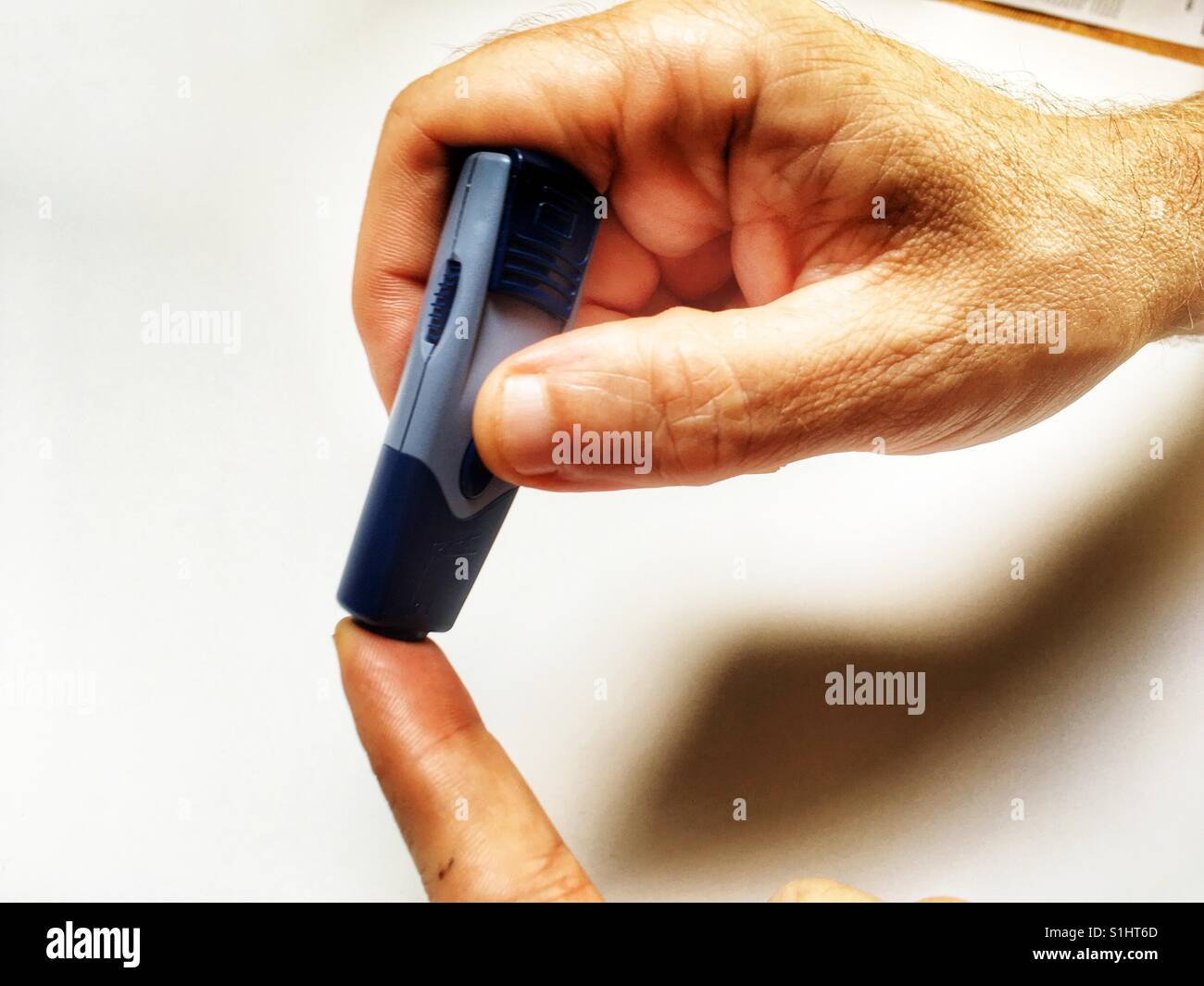 Diabetic patient pricking finger for blood to test sugar levels Stock