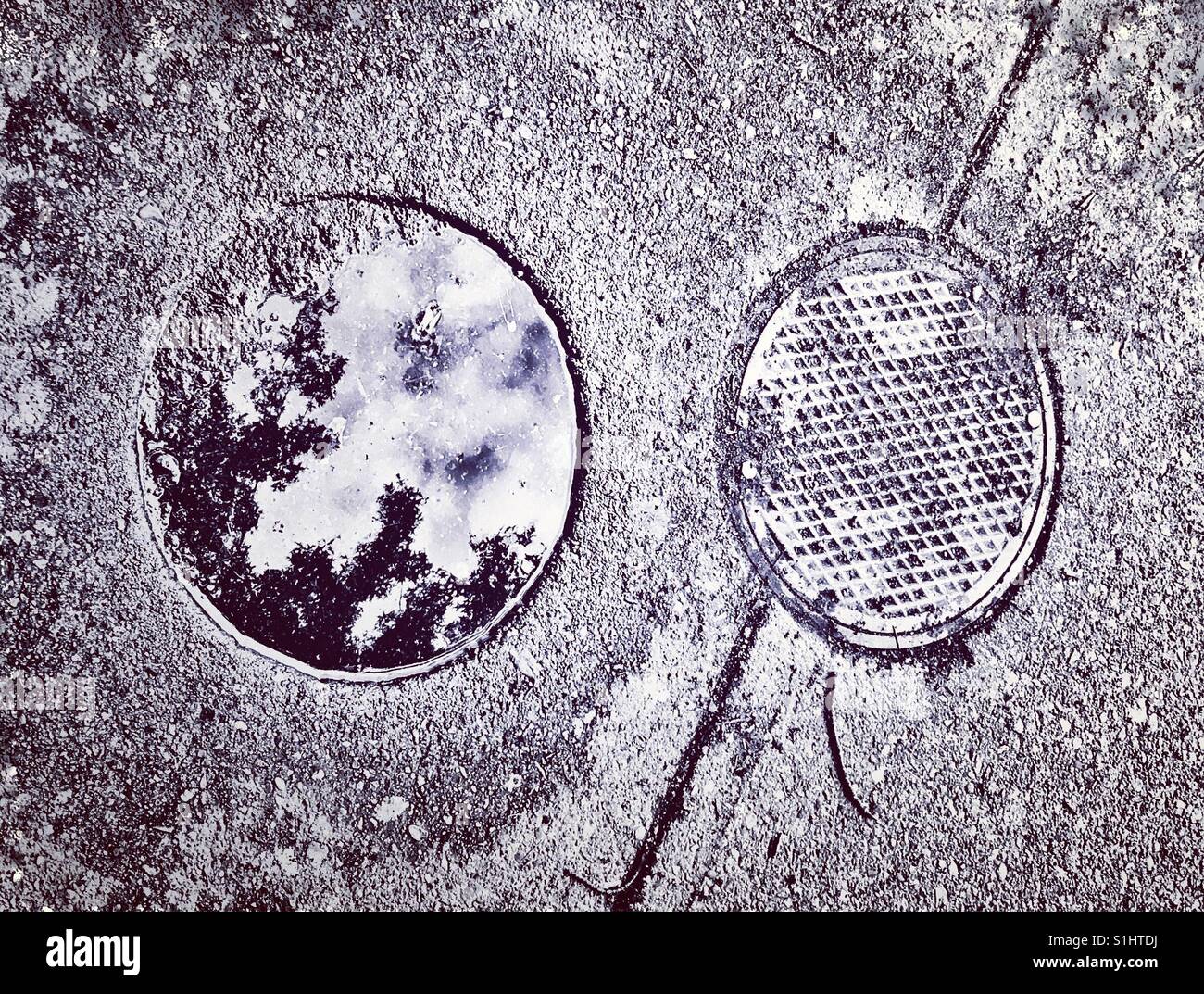 Reflection of water pooling on a manhole cover. - Smartphone Captured Stock Image