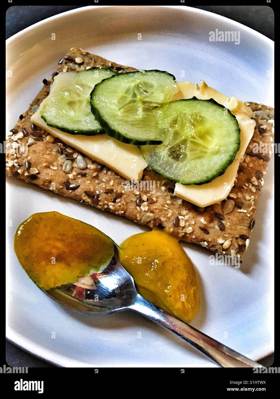 Strong cheddar and cucumber on a spelt cracker bread with English mustard. Stock Photo