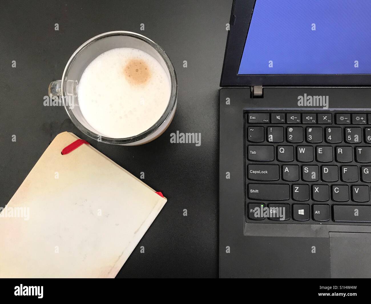 Notebook, computer and cappuccino over a black table - Smartphone Captured Stock Image