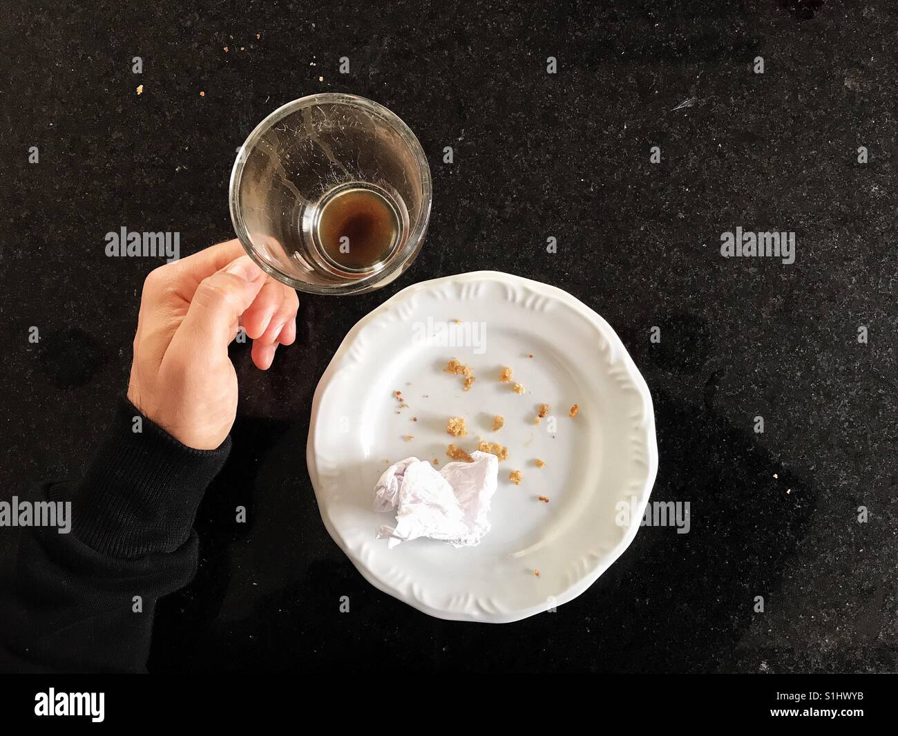 Person's view of a finished breakfast. Empty coffee cup and plate with crumbles - Smartphone Captured Stock Image