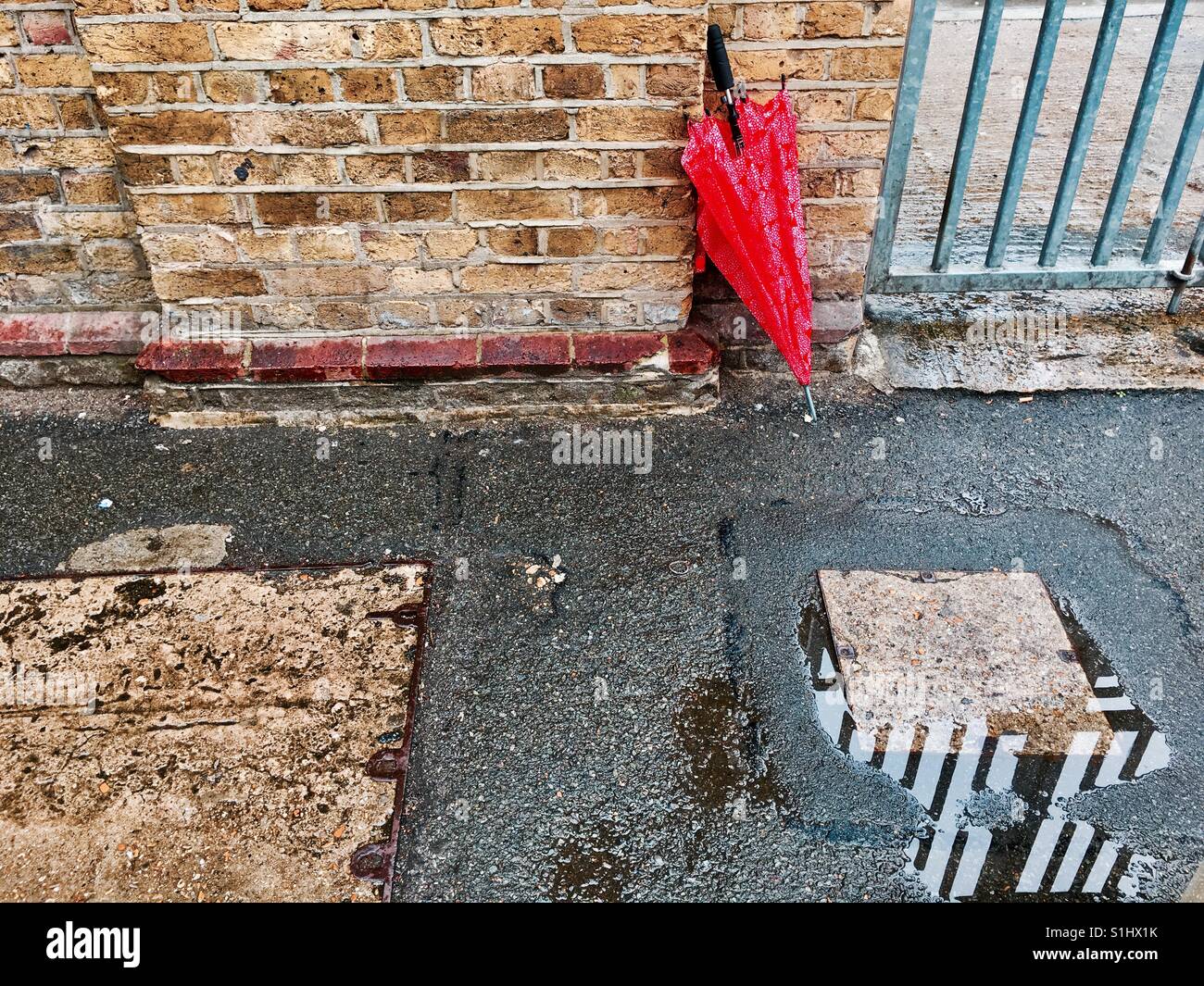Rainy day in London - red Ikea umbrella against brick wall - Smartphone Captured Stock Image