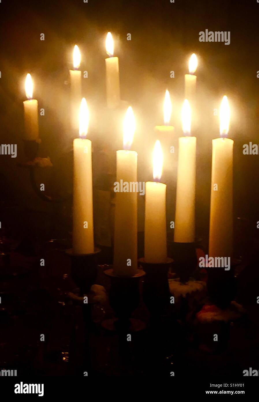 Candles burn brightly in a darkened room. - Smartphone Captured Stock Image