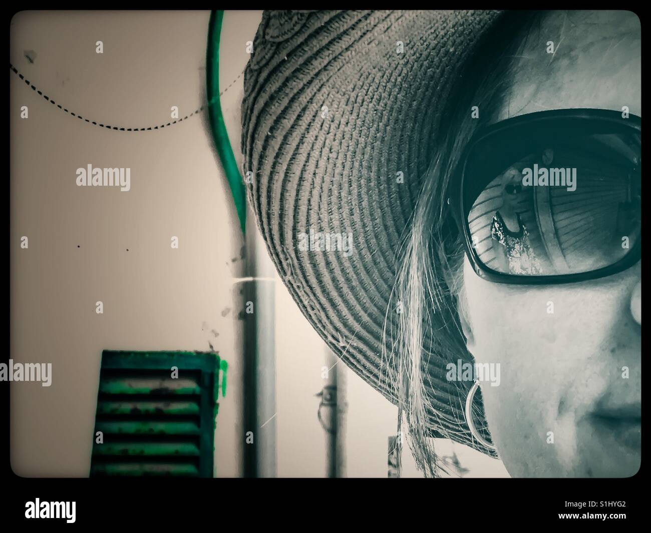 Woman in straw hat wearing sunglasses that reflect an image of her mother in them. Stock Photo