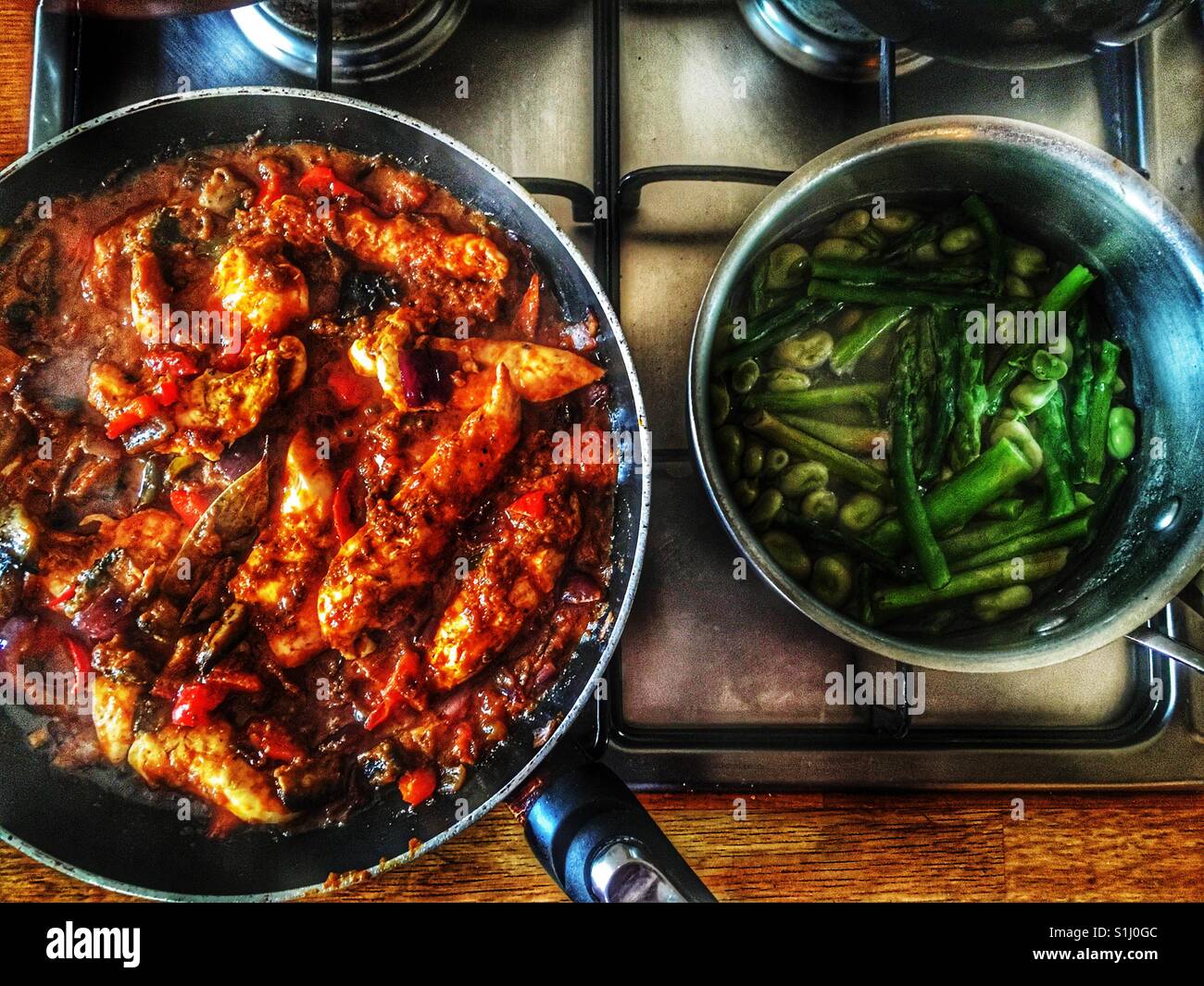 Chicken curry with rice and asparagus and board bean cooking on hob - Smartphone Captured Stock Image