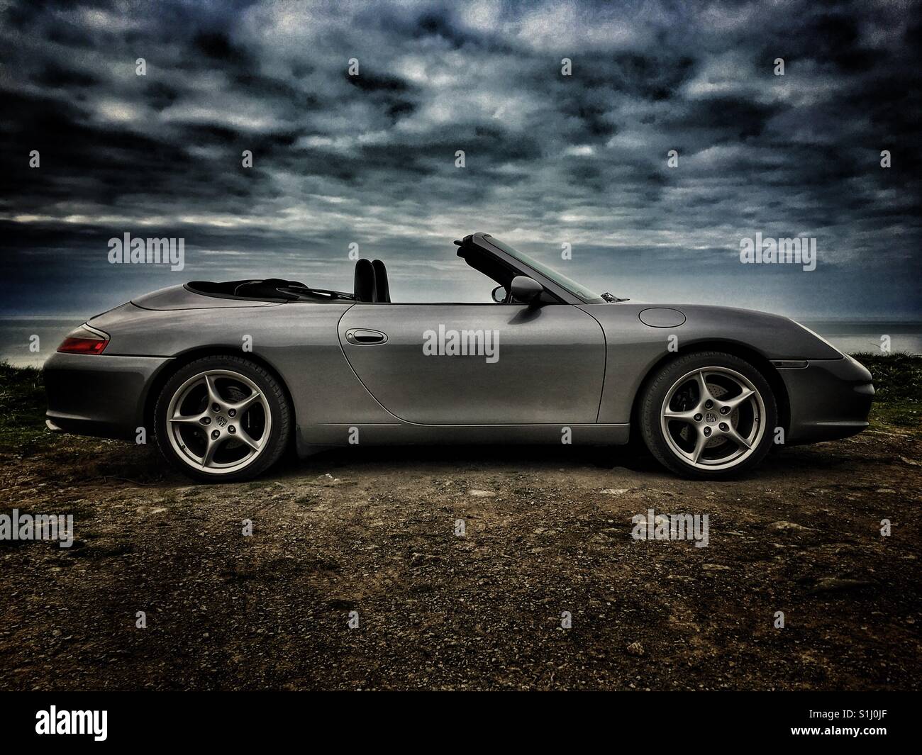 Porsche Carrera 911 convertible sports car, profile on coast line Stock