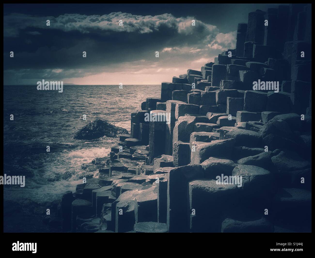 A blue toned image of the Famous UNESCO World Heritage site of Giant's Causeway, Co. Antrim, Northern Ireland, UK. This landscape is thought to be the result of volcanic activity 60 million years ago. - Smartphone Captured Stock Image