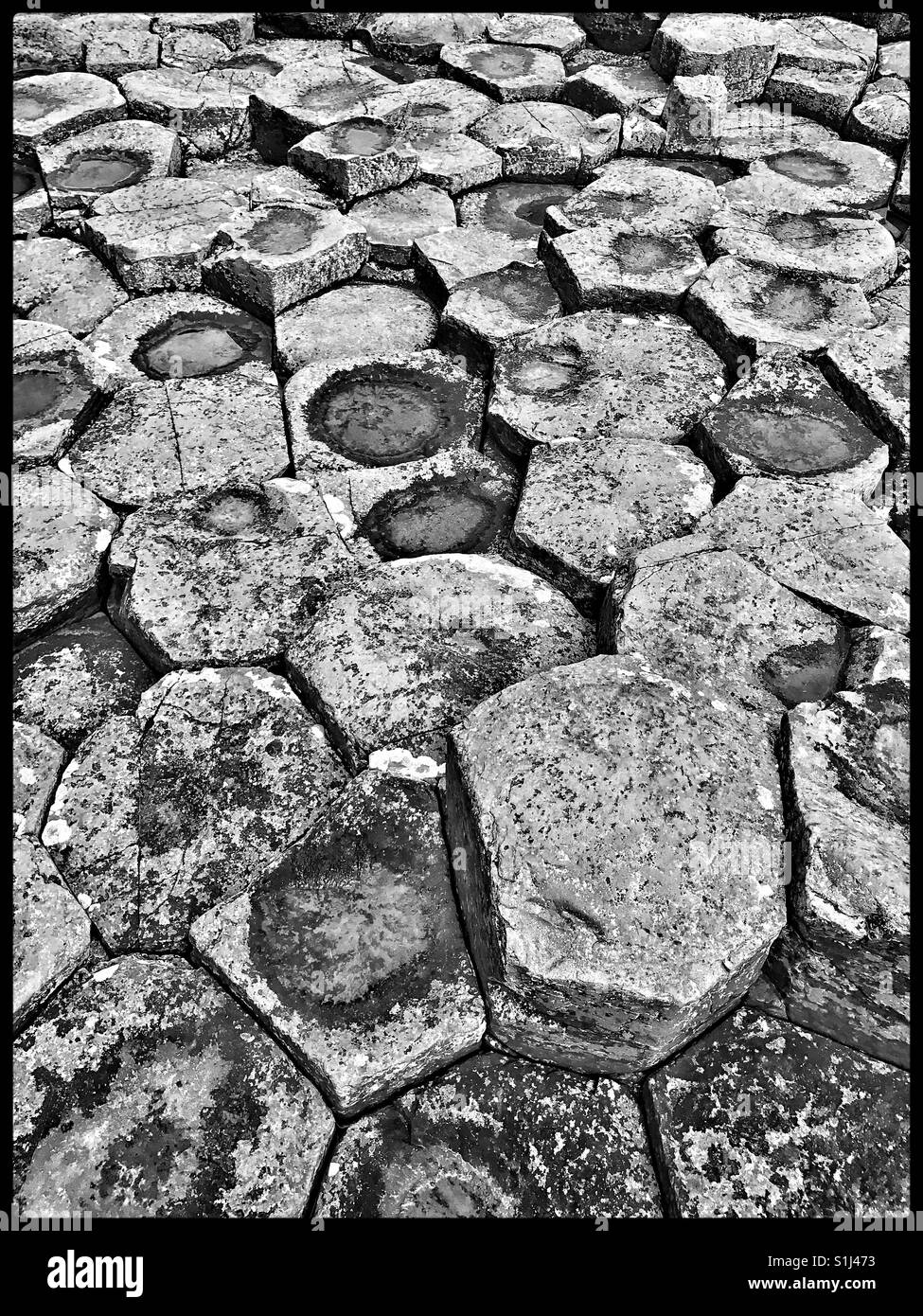 A monochrome pic showing details of the hexagon & pentagon basalt rock shapes at Giant's Causeway in Co. Antrim, Northern Ireland. Geologists believe these structures were created 60 million years ago - Smartphone Captured Stock Image