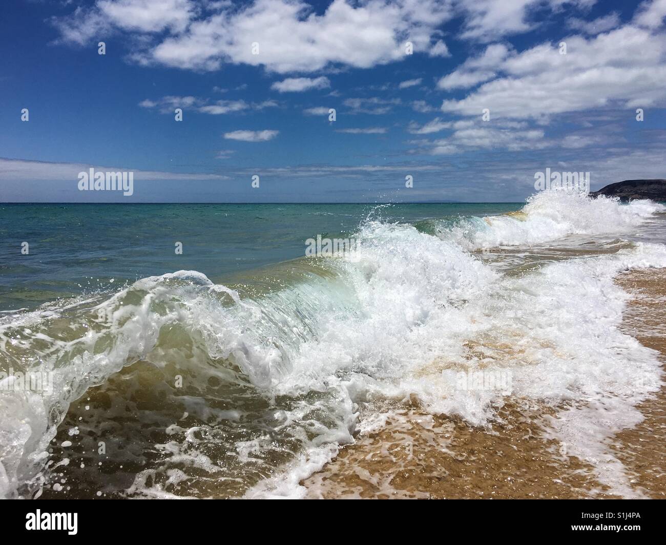 Waves crashing on the beach creating unusual shapes - Smartphone Captured Stock Image