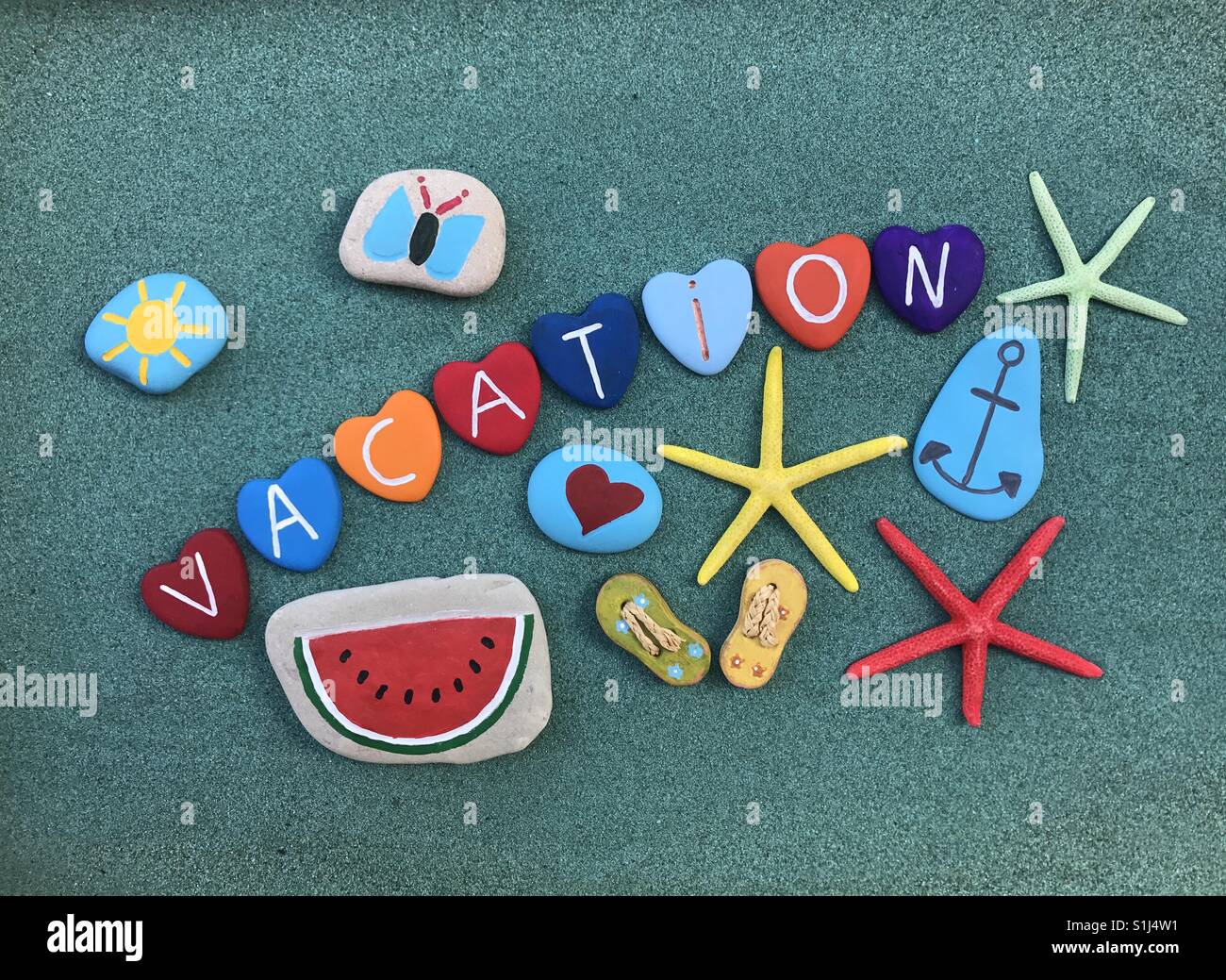 Vacation text with multicolored stones and starfishes composition over green sand - Smartphone Captured Stock Image