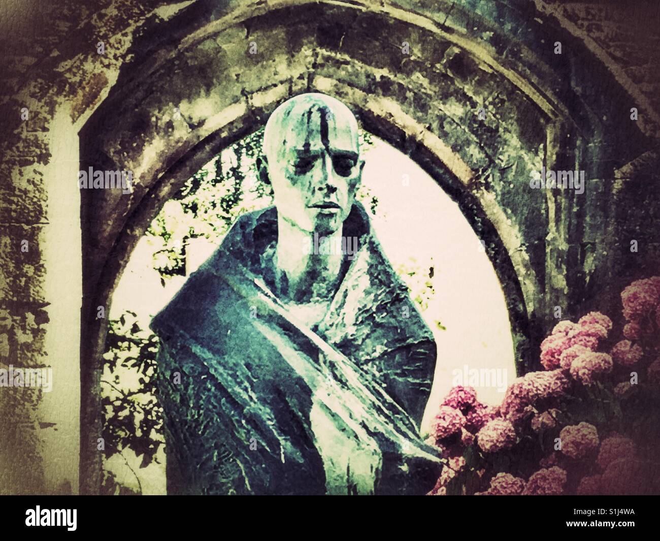 Pilgrim statue, arch and flowers in the ruins of the Bishop's Palace gardens, Wells, Somerset, England. - Smartphone Captured Stock Image