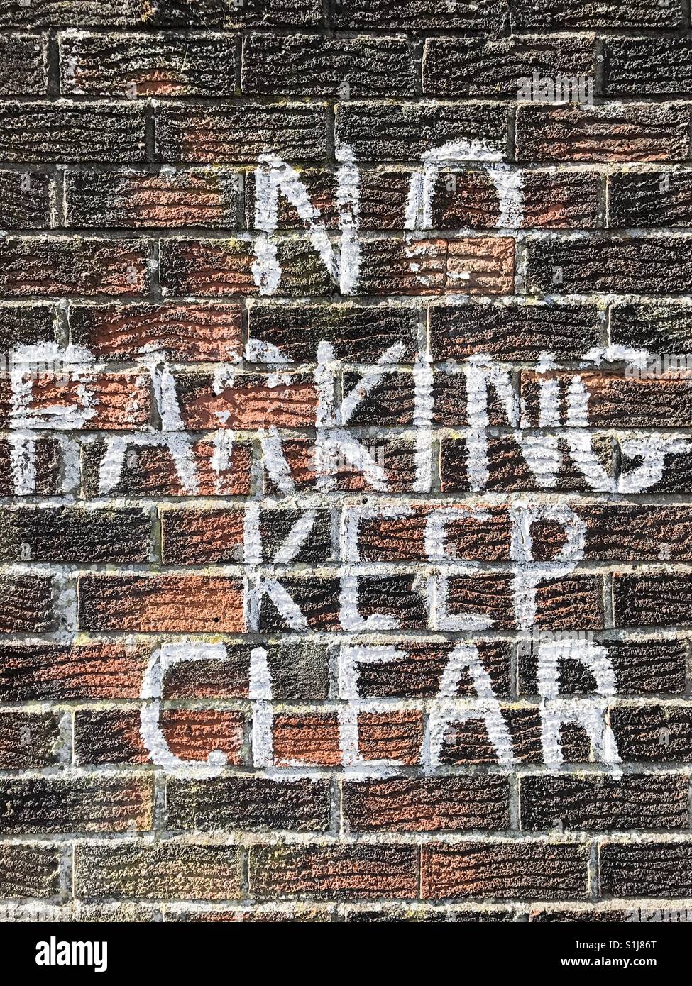 A hand painted sign on a brick wall saying 'NO PARKING KEEP CLEAR'. - Smartphone Captured Stock Image