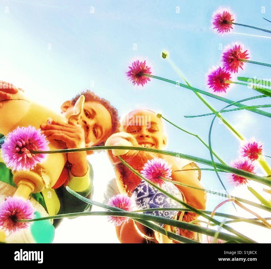 Two children playing amongst Chive flowers. - Smartphone Captured Stock Image