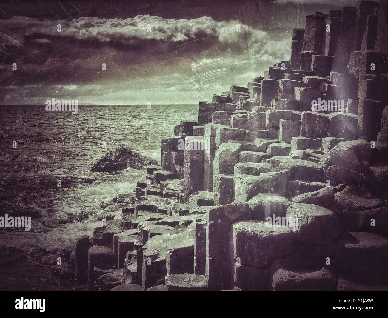 A grunge and antique effect image of the famous basalt rock columns at Giant's Causeway, in Co. Antrim, Northern Ireland. A moody image that has multiple uses. Photo © COLIN HOSKINS. - Smartphone Captured Stock Image