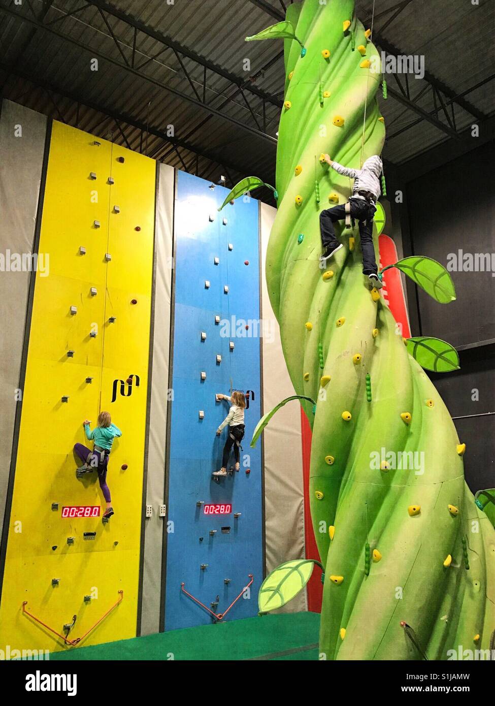 Children climb different structures at an indoor climbing park. Stock Photo
