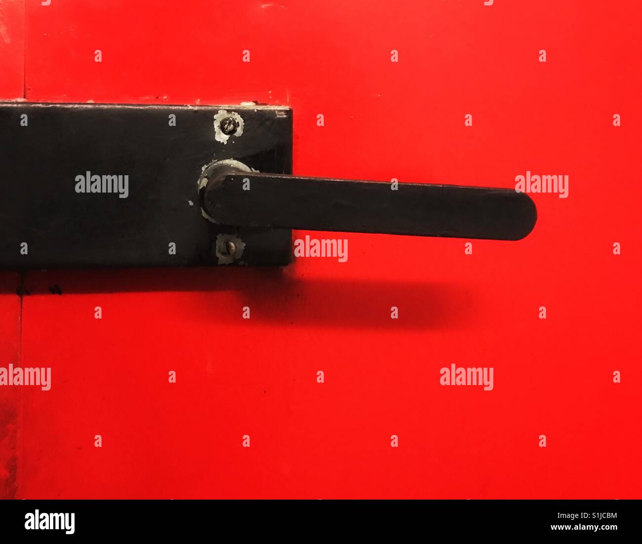 Black door knob on a red door. Close up shot Stock Photo