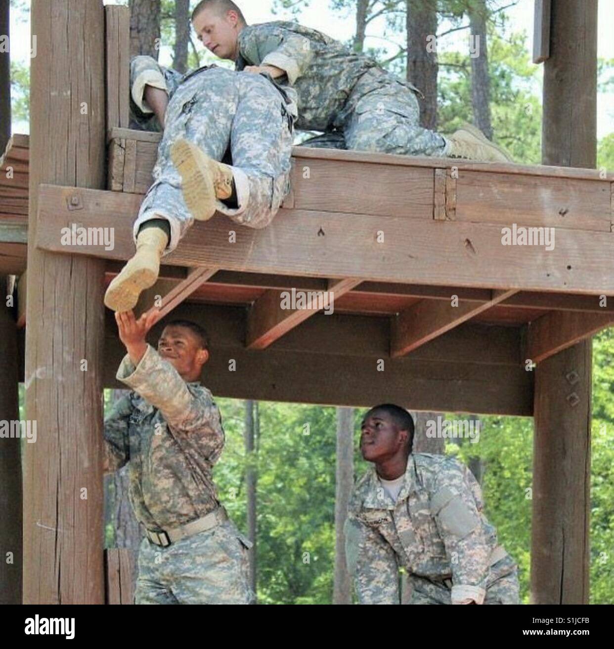 Soldiers helping each other climb a tower during Basic Combat Training (BCT). Stock Photo