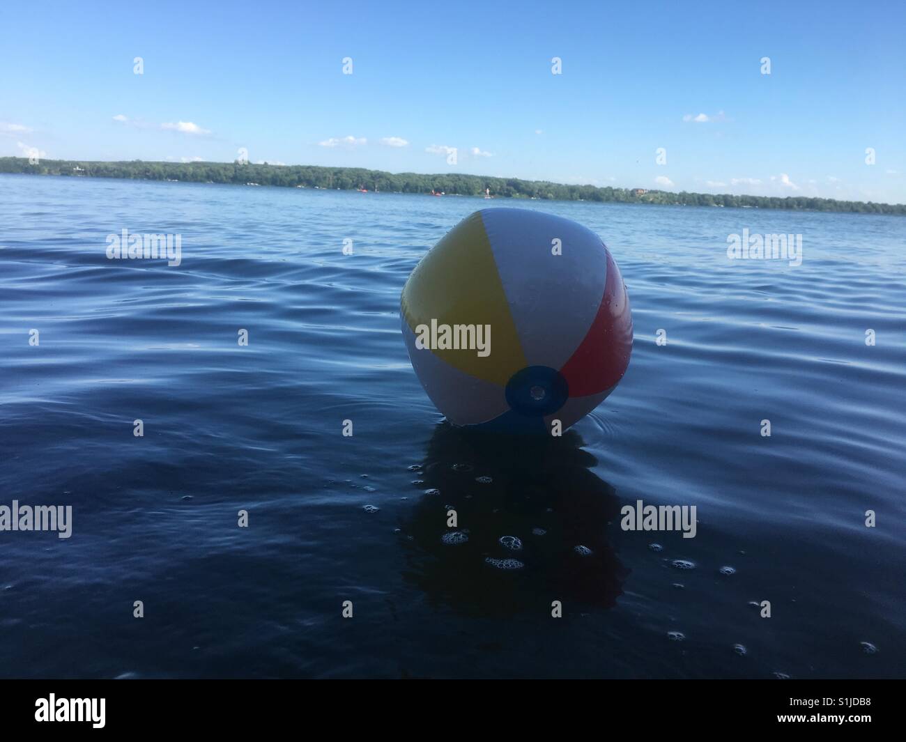 Summer beach ball drifting in the water on the lake Stock Photo