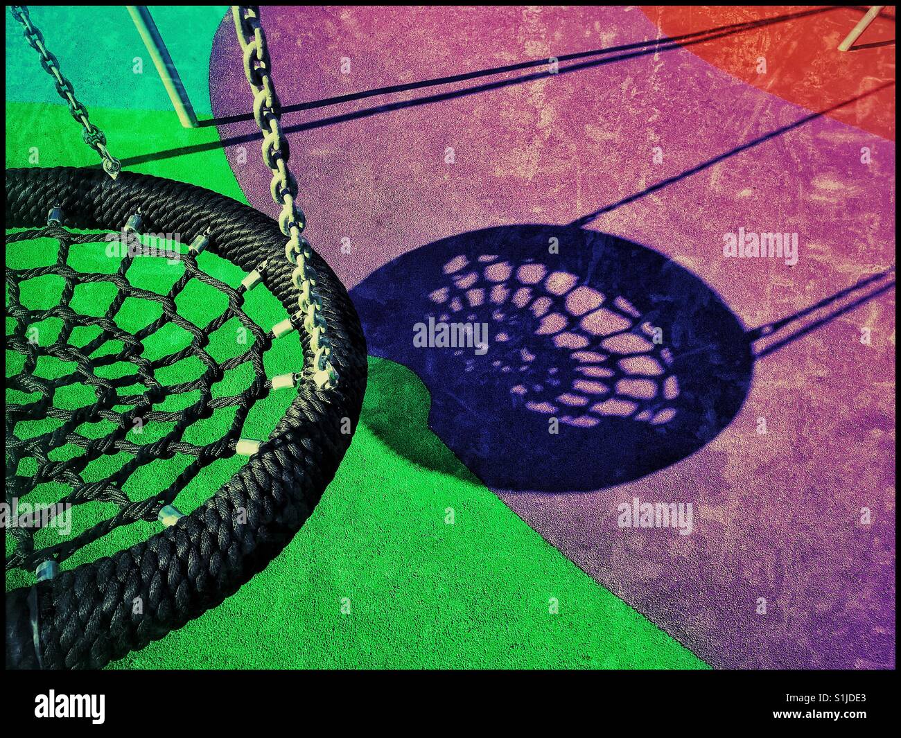 A colourful grunge effect image of a lonely swing in a children's playground or play park. It's a bright summer afternoon so the shadows are well defined. Photo Credit © COLIN HOSKINS. - Smartphone Captured Stock Image