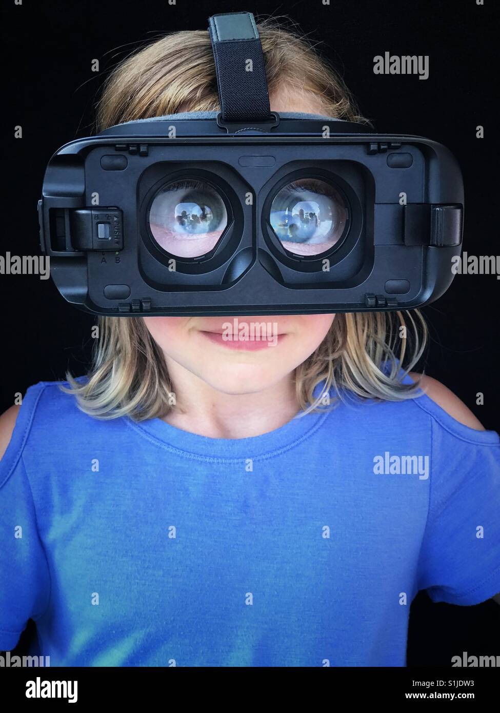 A girl wears VR goggles without a device, showing highly magnified eyes. Stock Photo
