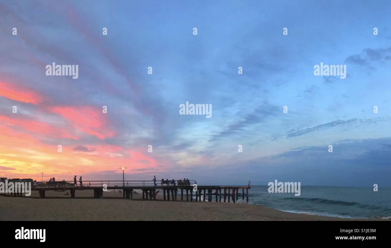 A sunset evening down the shore, colorful clouds and peaceful waves Stock Photo