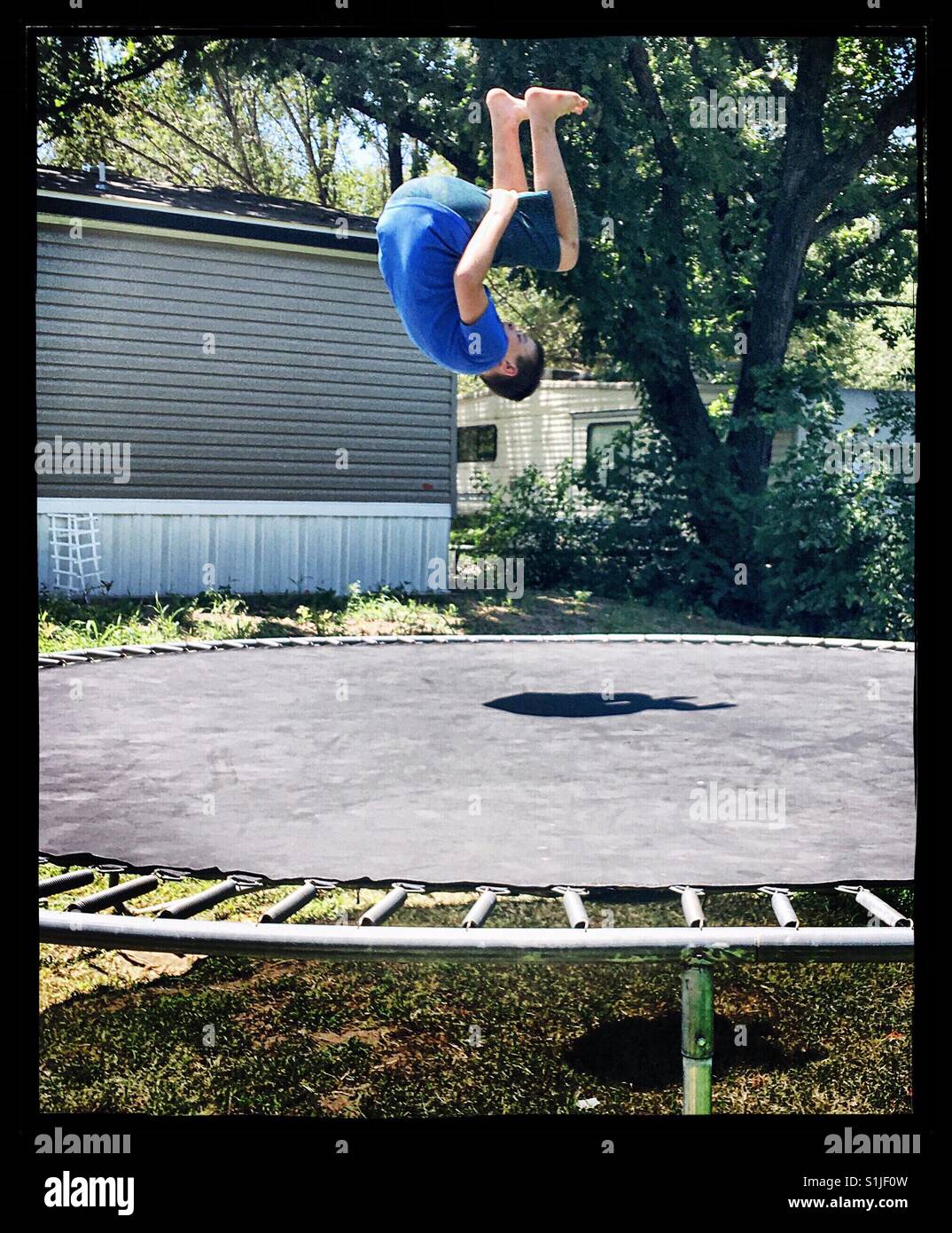 Boy doing a flip on trampoline Stock Photo Alamy