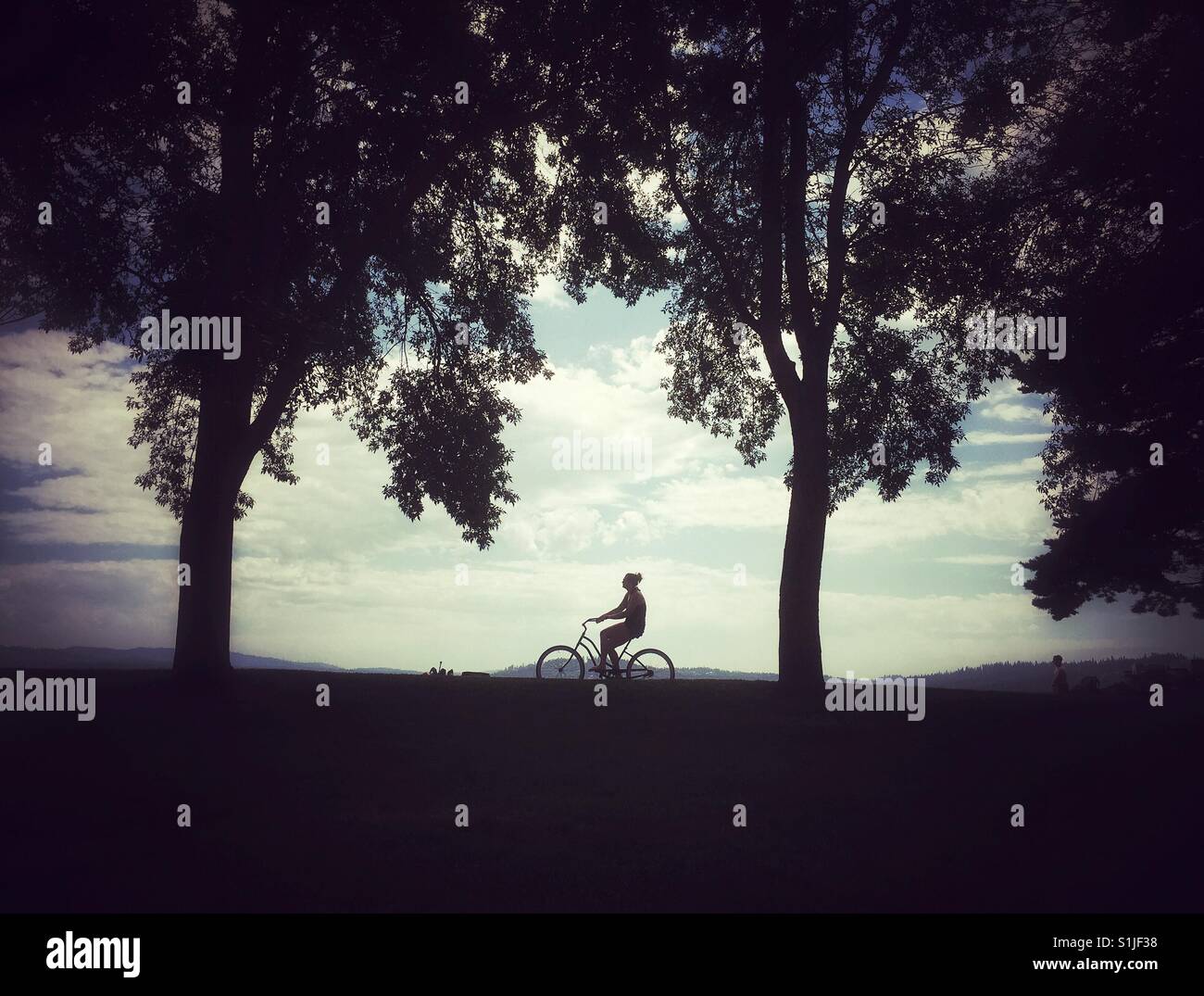 Silhouette of a woman riding bike near Coeur d'Allene lake in Northern Idaho Stock Photo