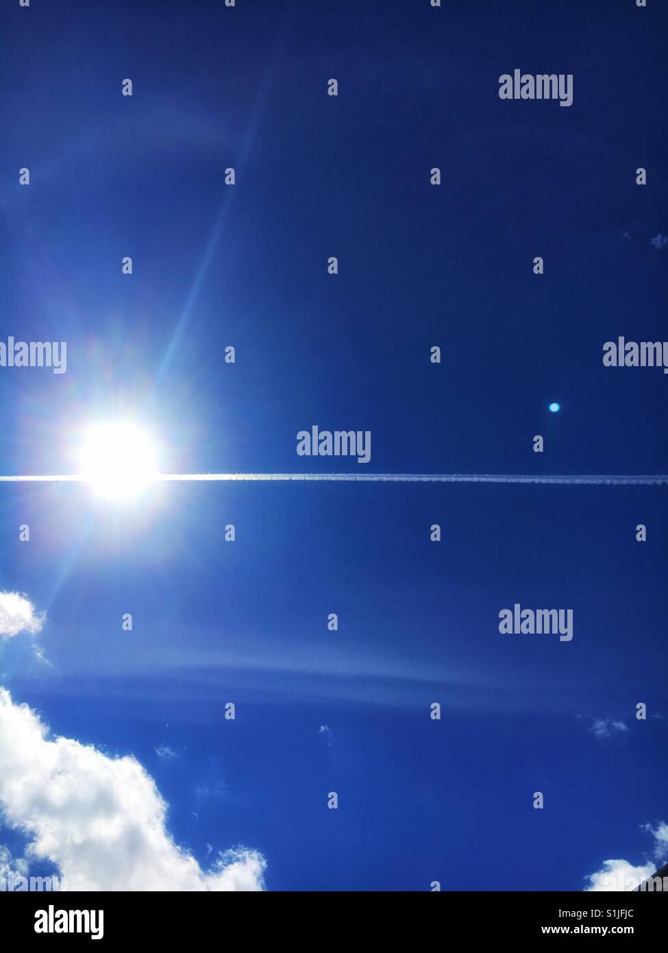Bright summer day with con trails through sun - Smartphone Captured Stock Image