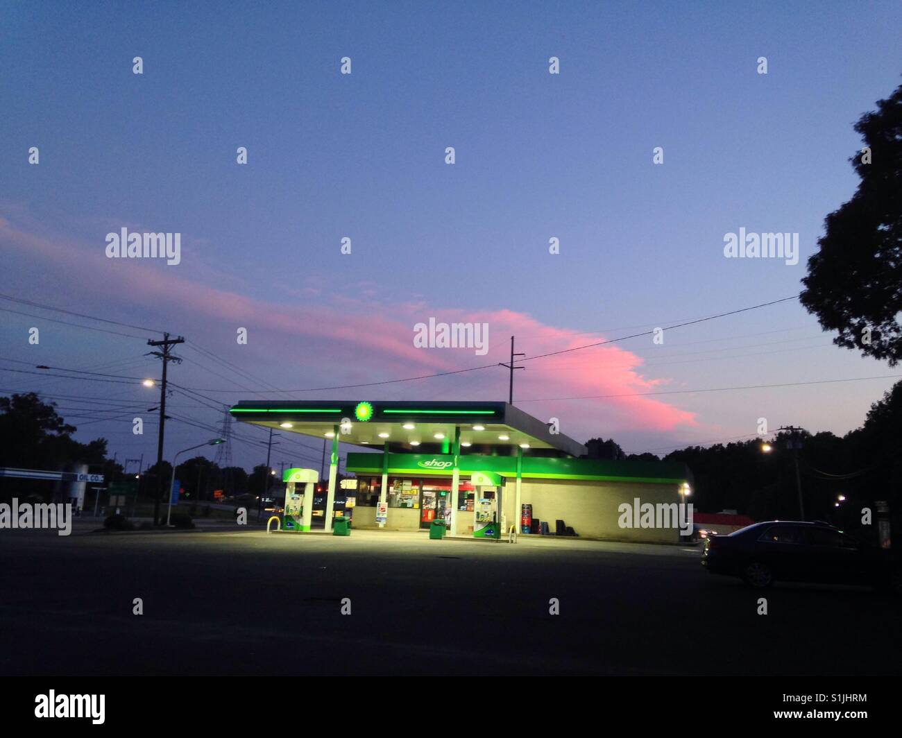 Pink cloud in blue sky over green gas station in NC Stock Photo