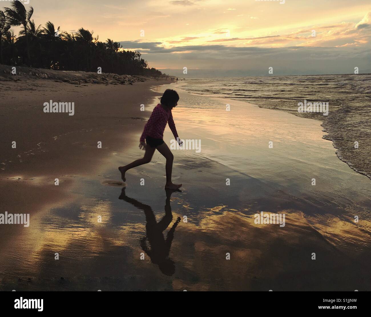 Little girl running on the beach Stock Photo