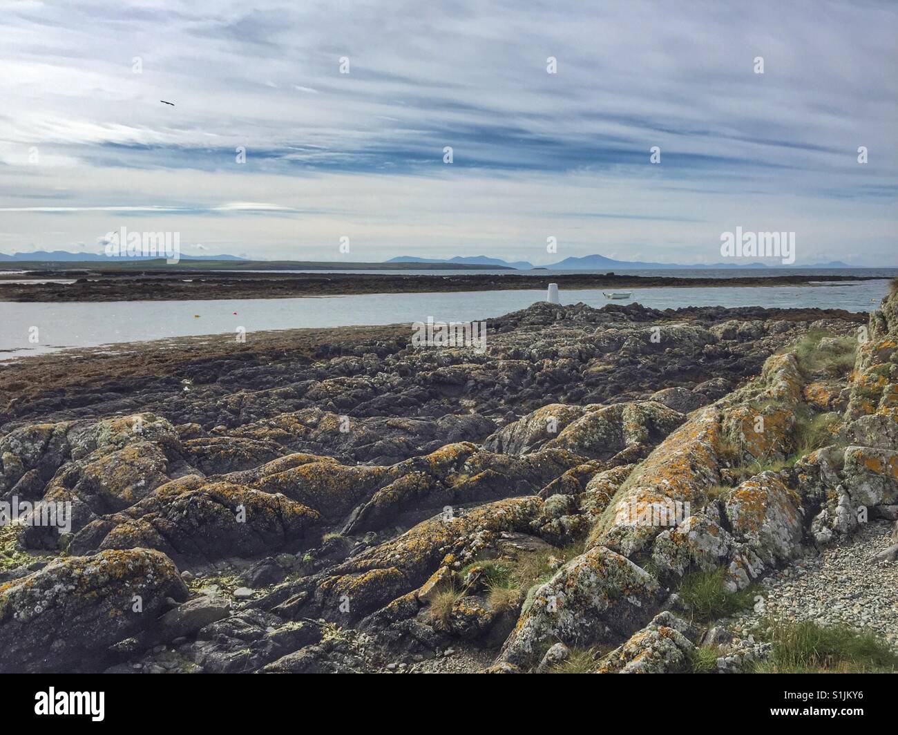 Rocks with view to snowdonia from Rhosneigr beach looking to Llyn Peninsula, North Wales, Anglesey - Smartphone Captured Stock Image