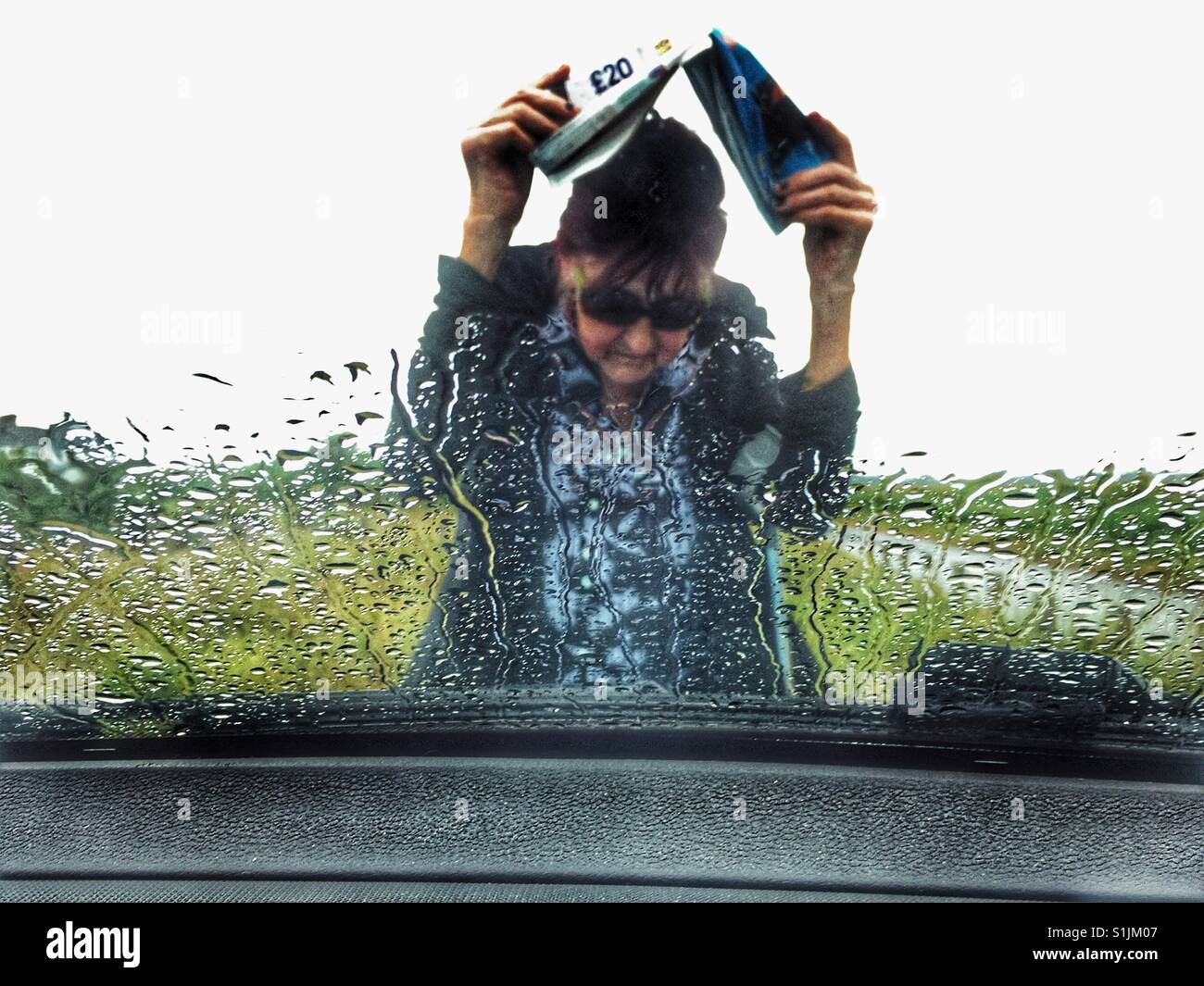 Woman running back to her car during a summer downpour, Shingle Street, Suffolk, UK. - Smartphone Captured Stock Image