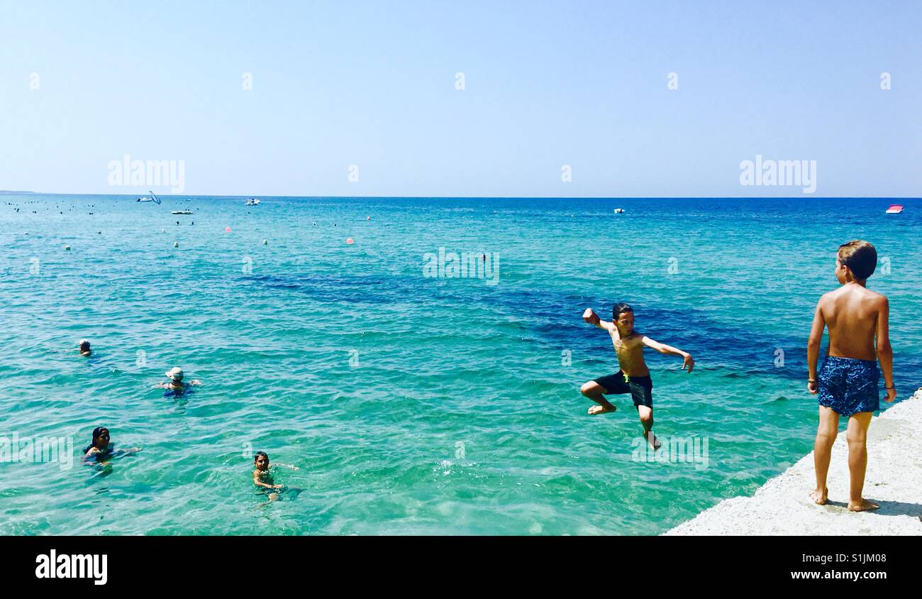 Greek boys jumping into the Aegean Sea in chalkidiki, Greece. Stock Photo