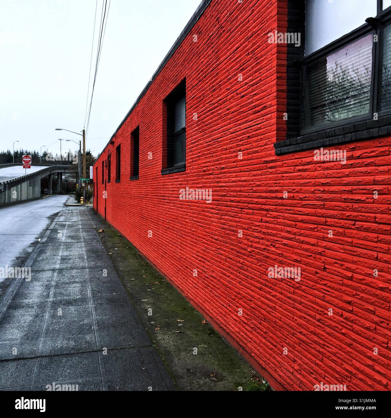 Long brick wall painted deep bright red in Georgetown neighborhood in Seattle Stock Photo