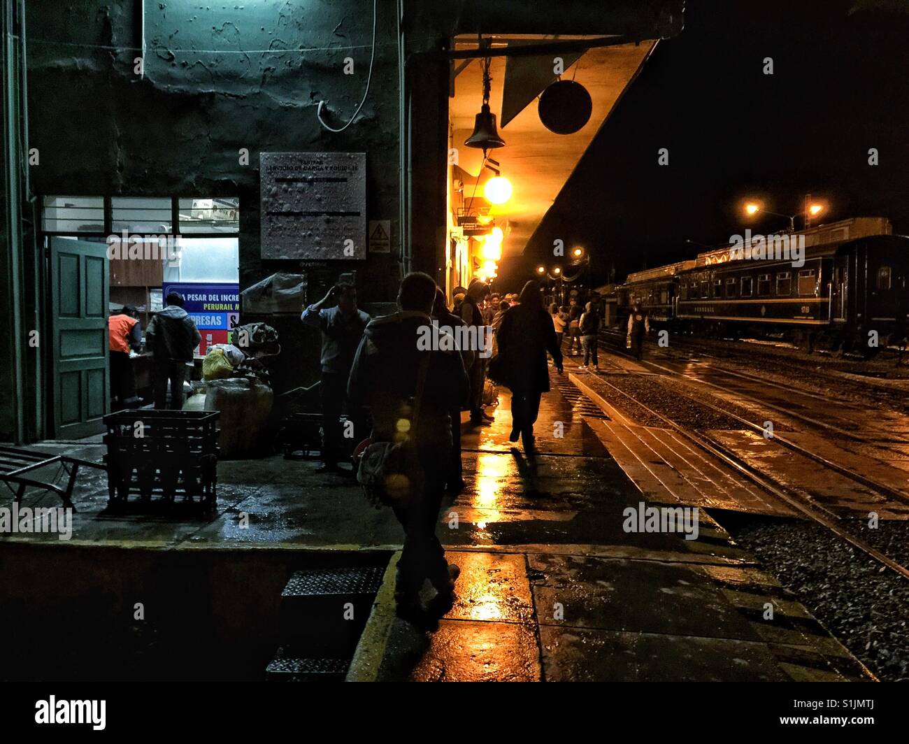 Lights reflect in wet surface of the train station in Ollantaytambo in Peru at night Stock Photo