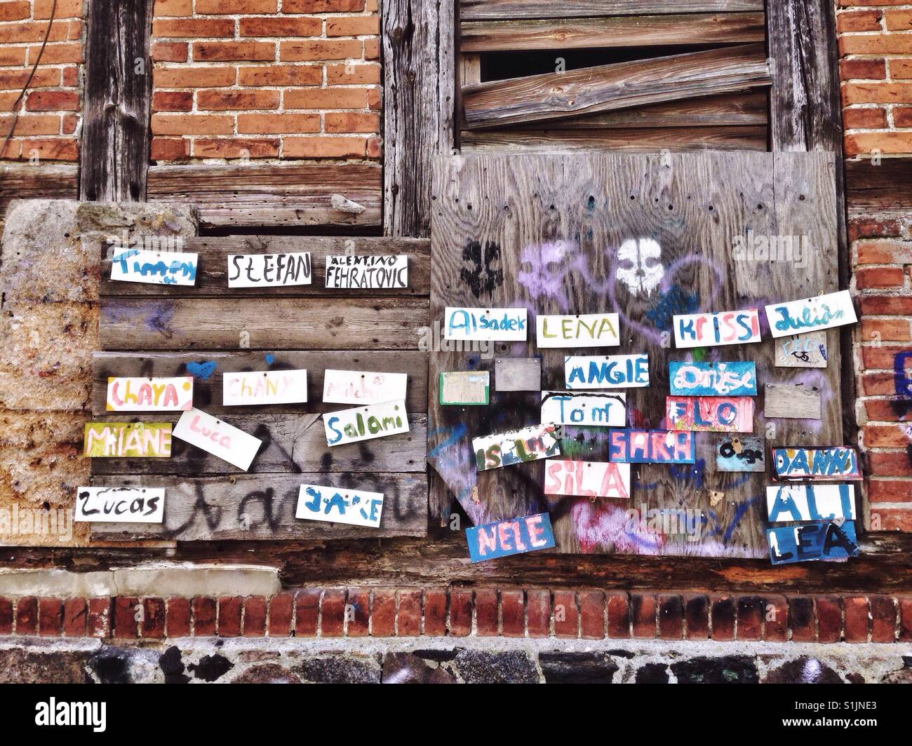 Names on paper slips on the wall of a boarded up house Stock Photo