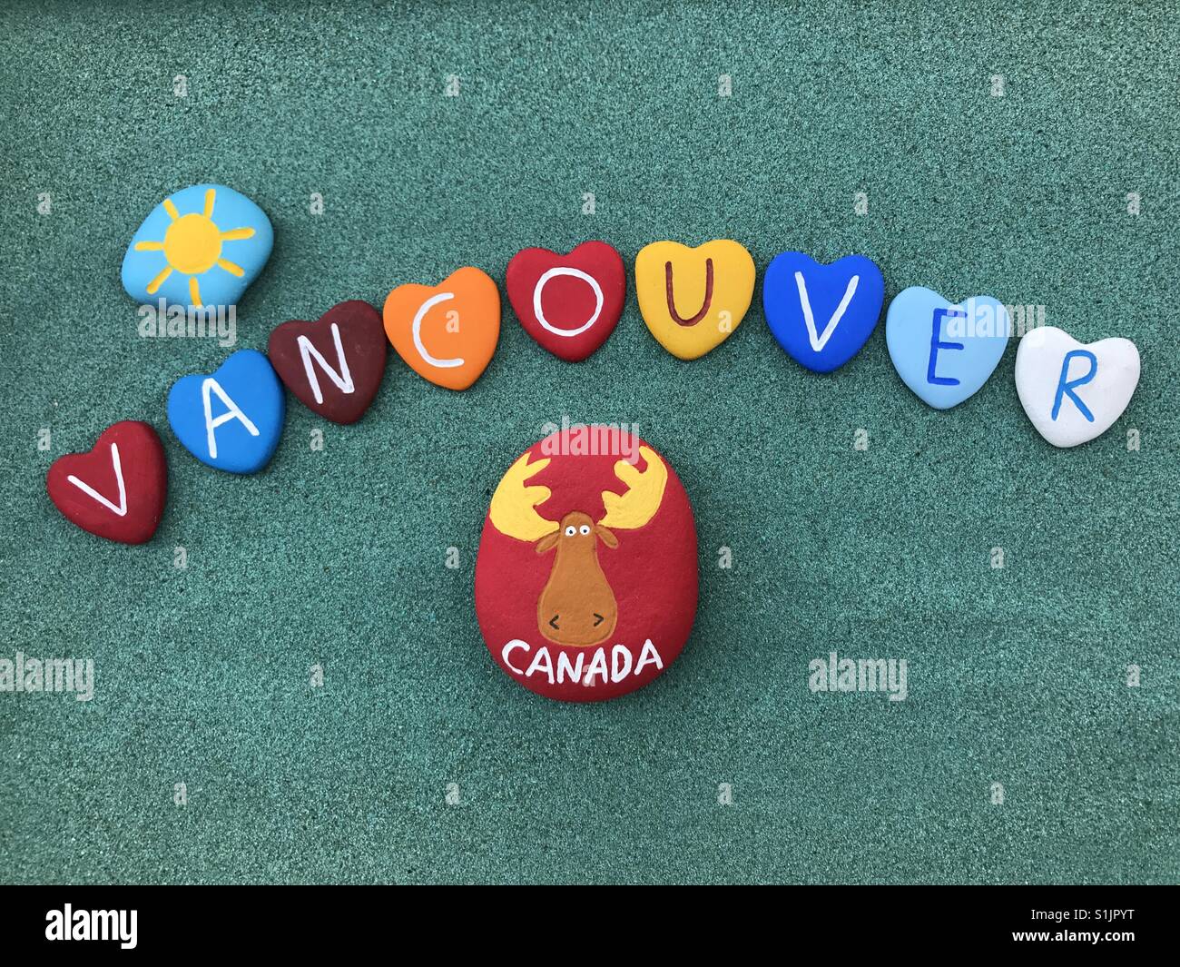 Vancouver, Canada, souvenir with multicolored heart stones over green sand - Smartphone Captured Stock Image